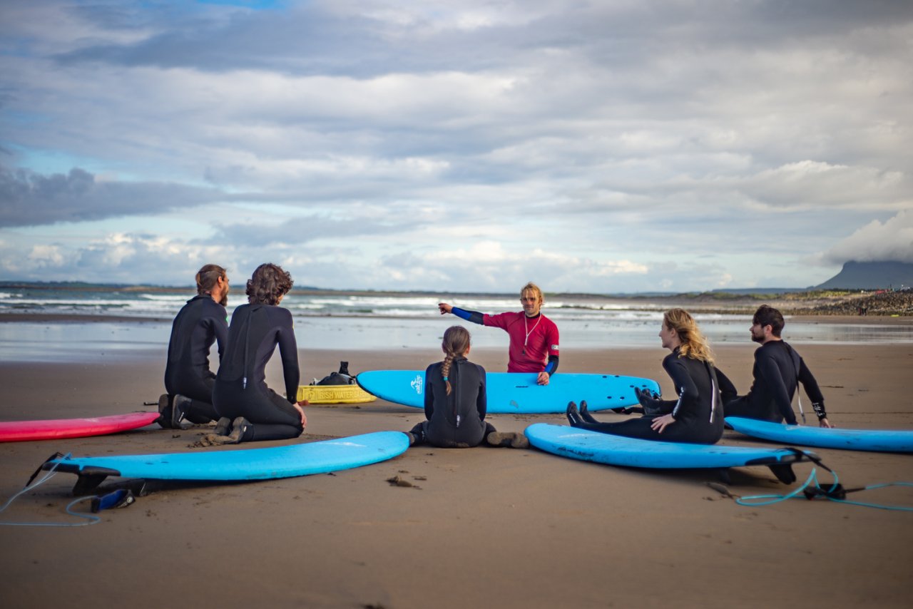 surfing instrctor on beach with five people 