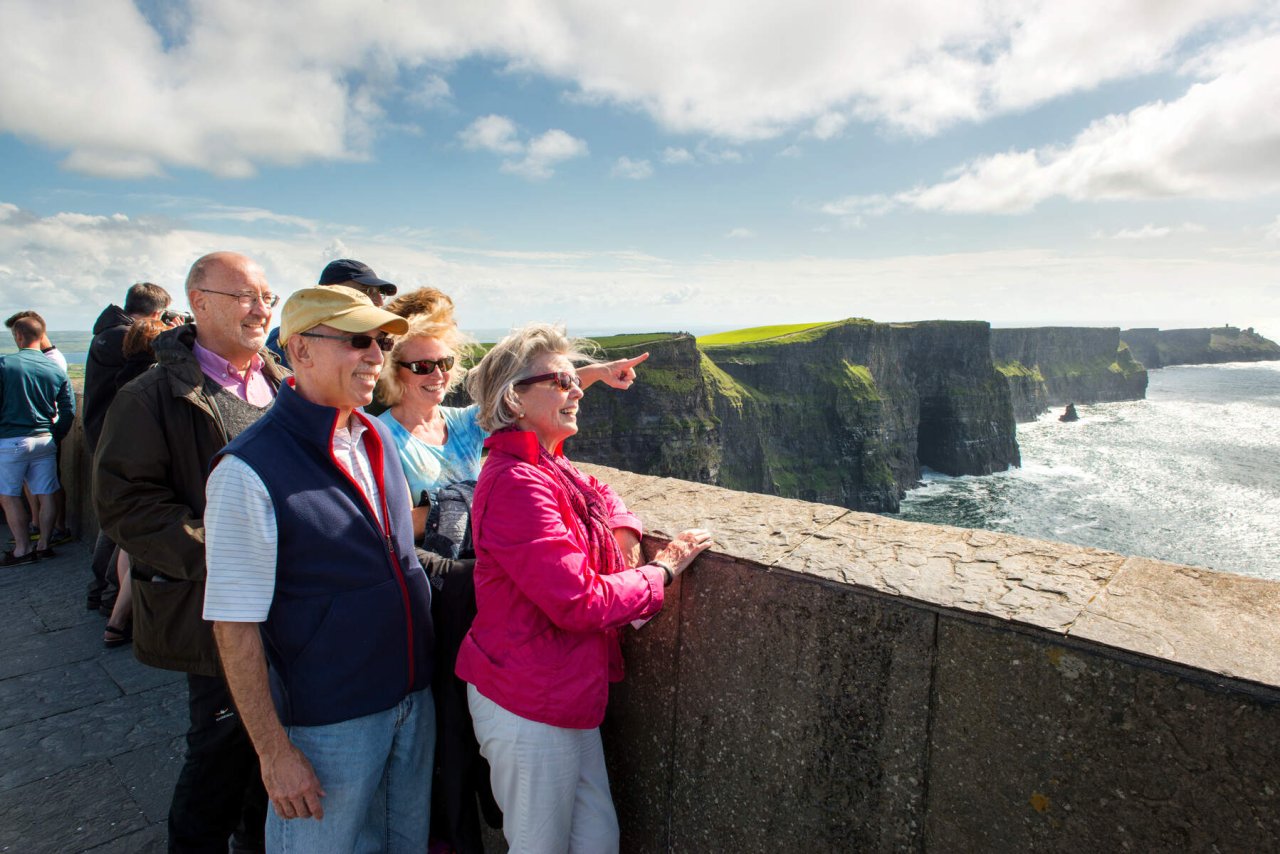 people looking beside cliffs and the sea